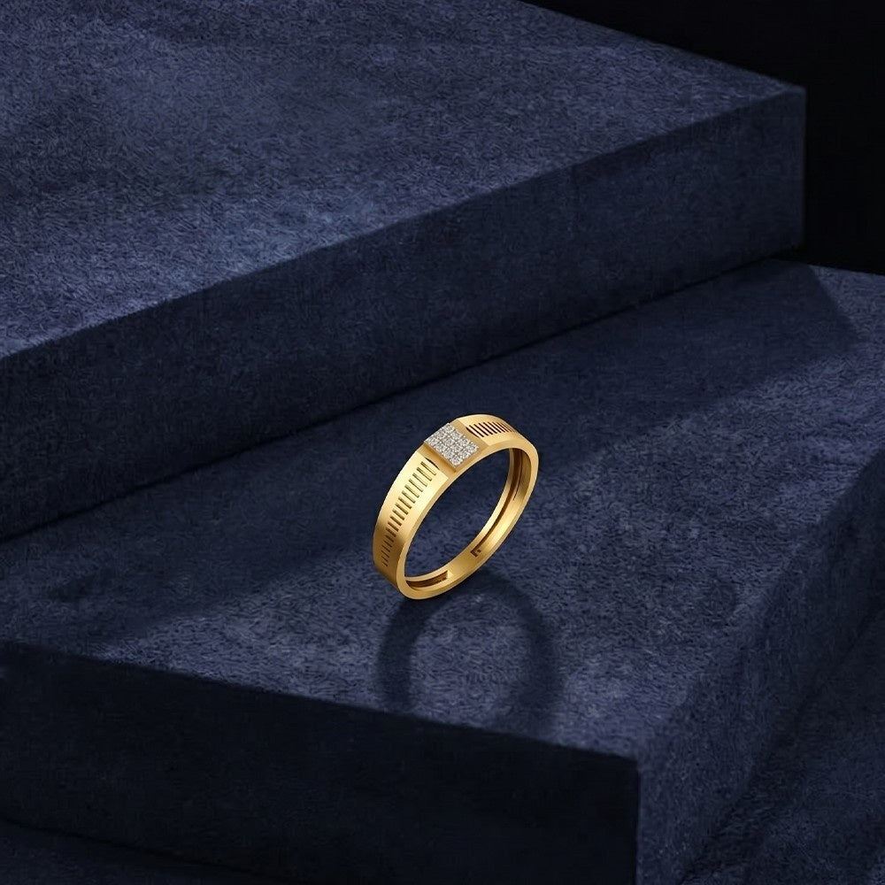 Gold ring with diamond accents on a dark blue surface.