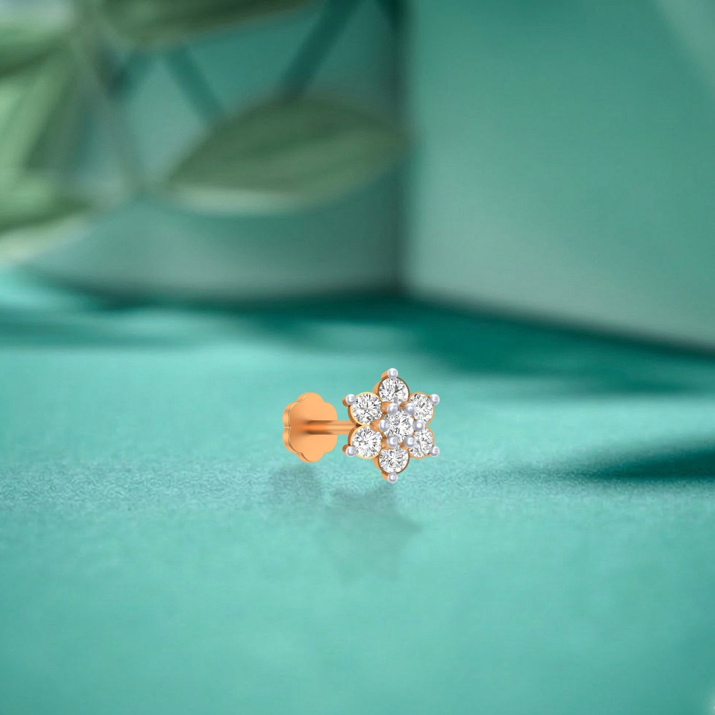 yellow gold and diamond stud nose pin with floral design on a teal background