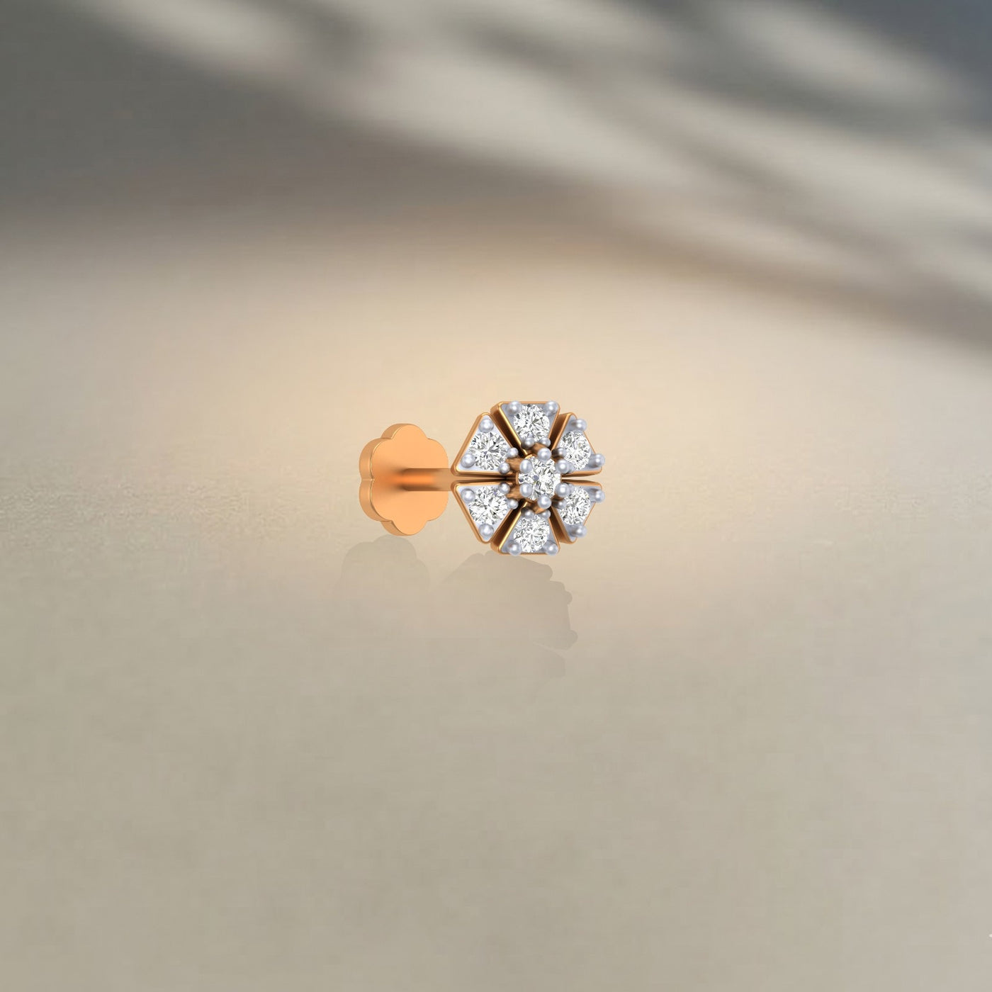 Yellow gold and diamond stud nose pin on a light background