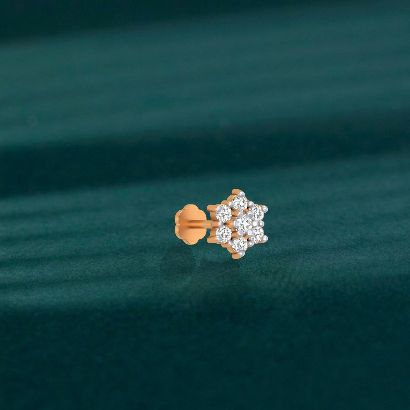 yellow gold and diamond stud nose pin with diamonds on a green fabric background