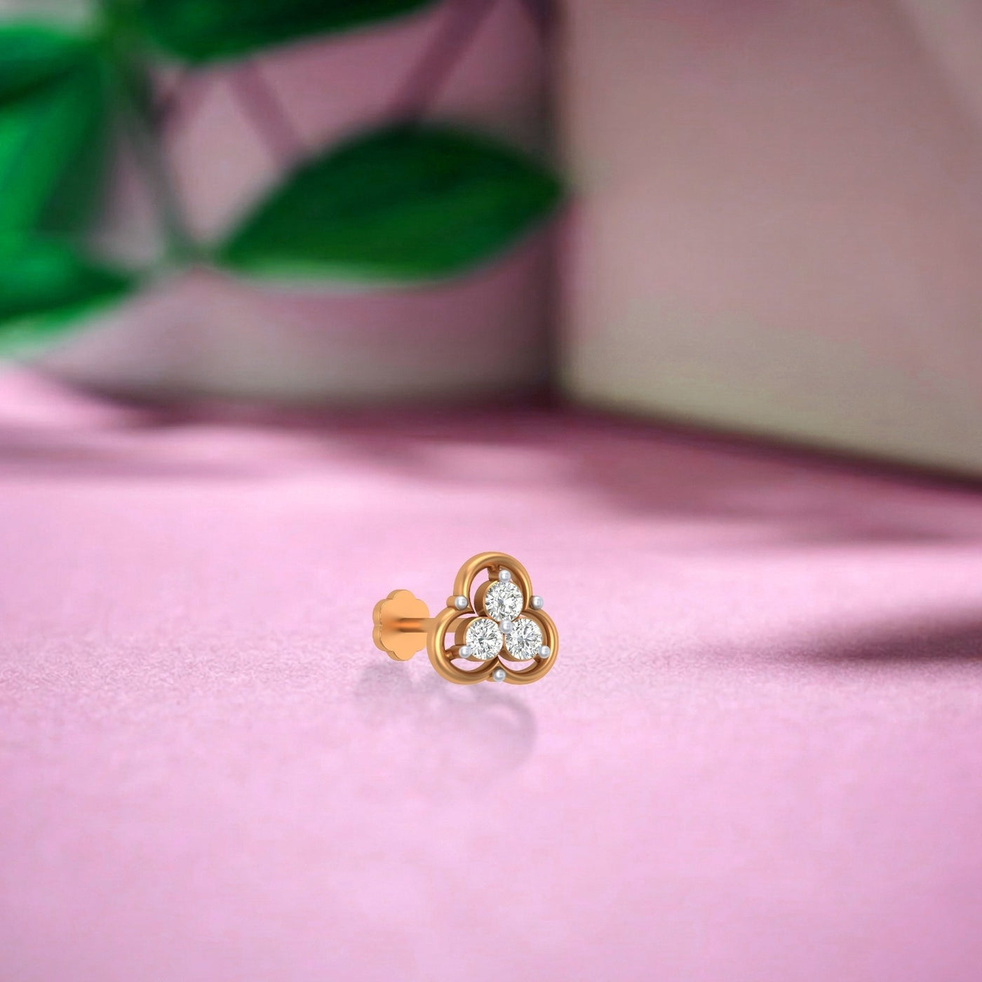 yellow gold and diamond stud nose pin with three diamonds on a pink fabric background