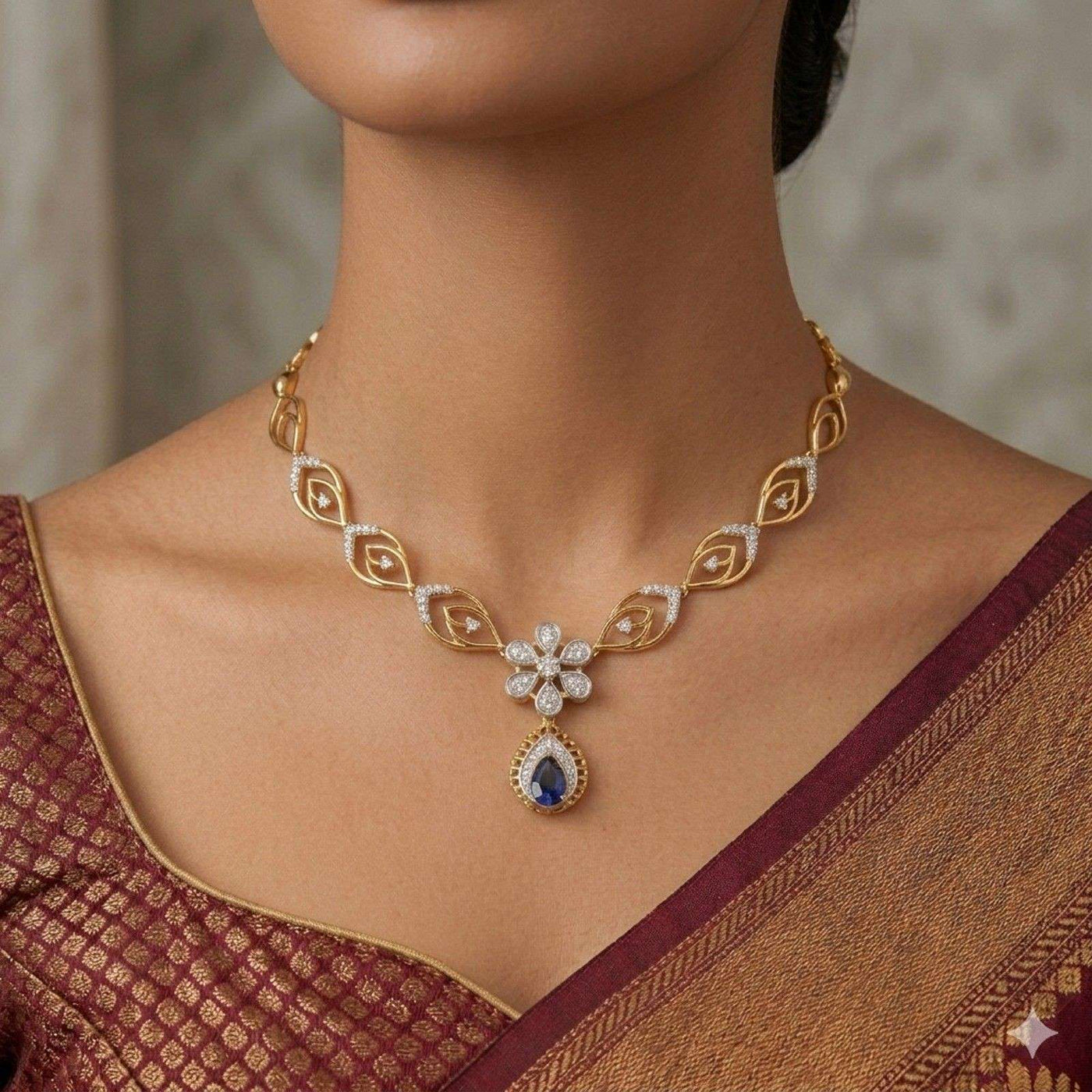 Gold and diamond necklace with a blue gemstone worn by a person in a maroon saree.