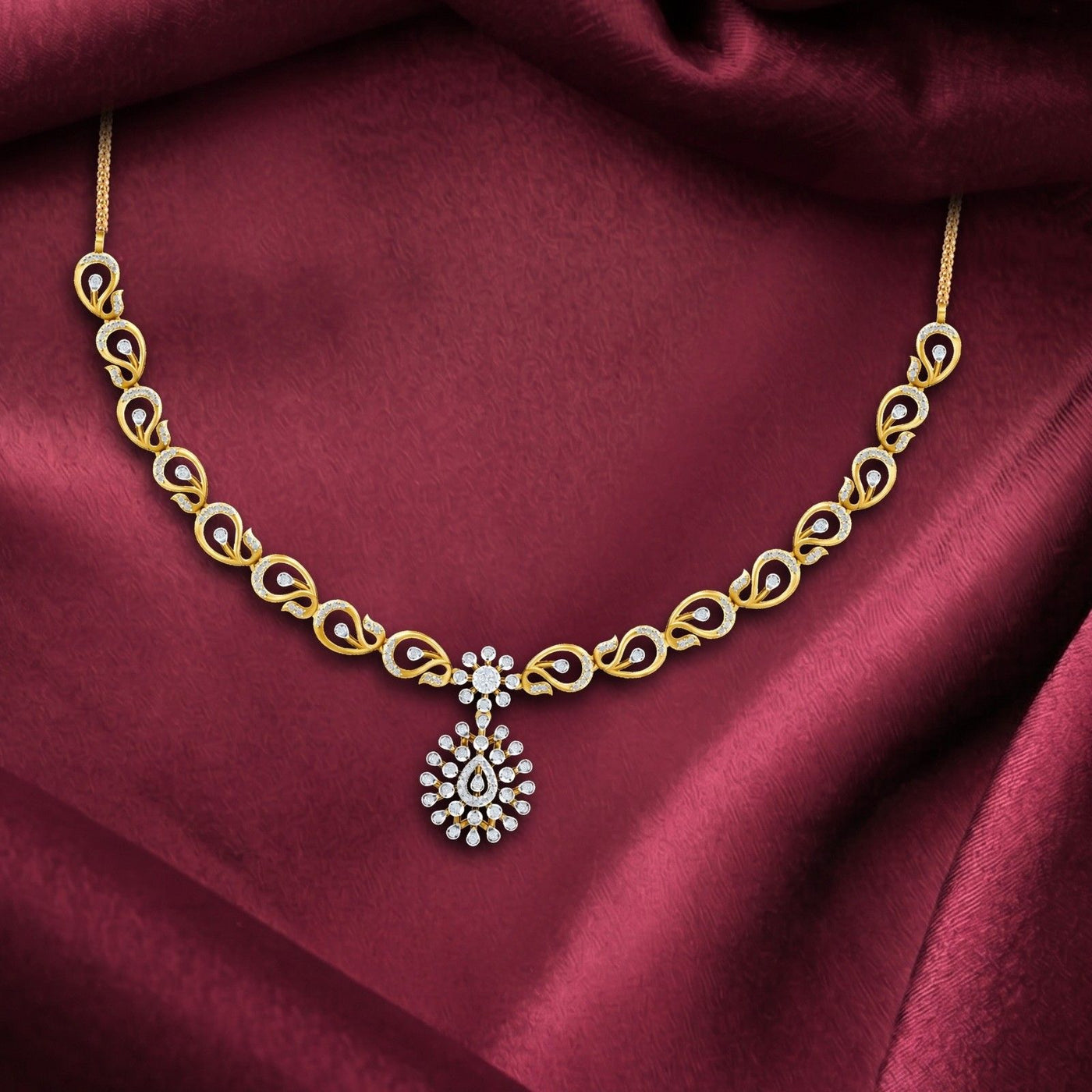 A delicate gold and diamond  necklace featuring a repeating leaf pattern, displayed on a red fabric background.