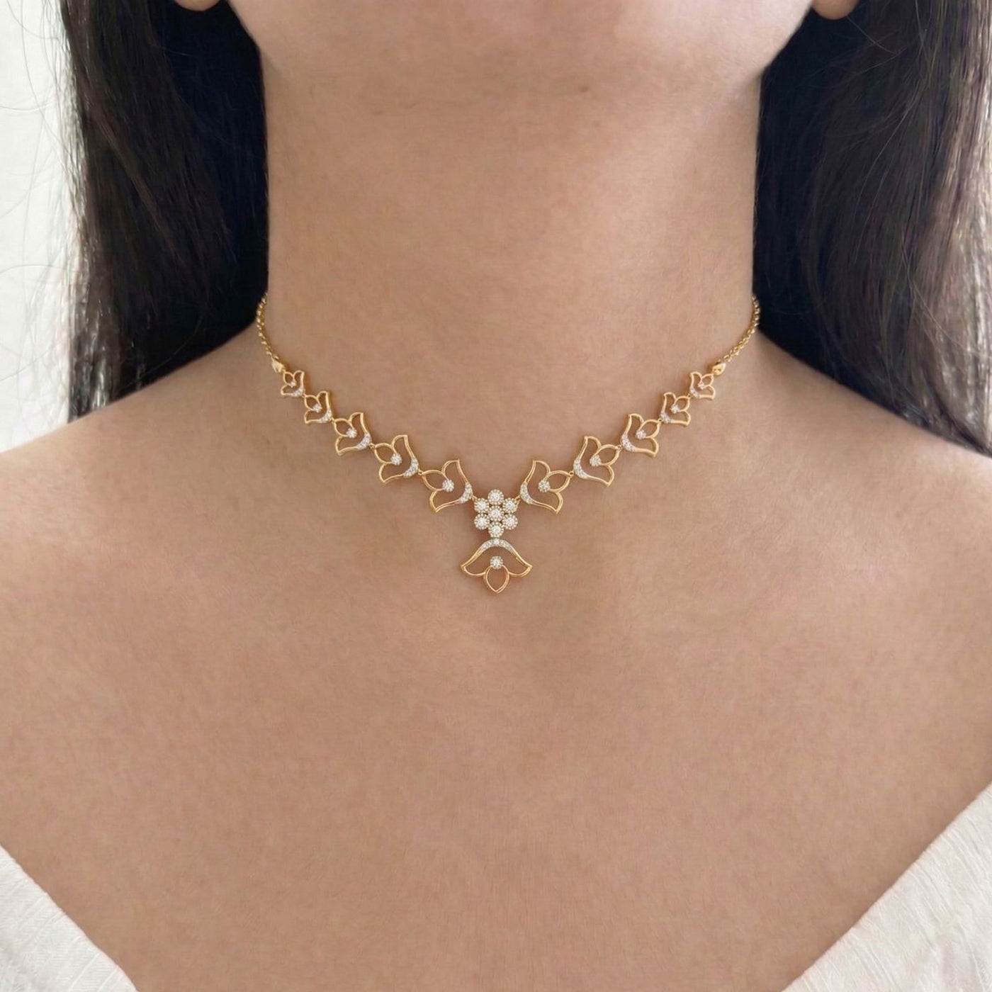 Gold necklace with floral design worn by a person