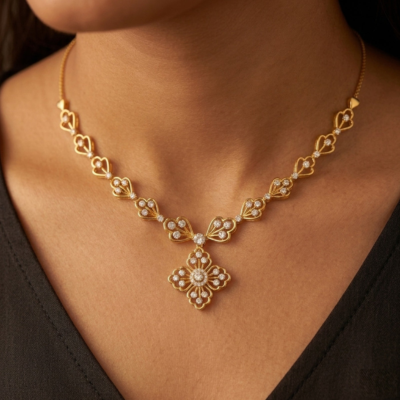 Gold and diamond necklace with floral pendant on a person wearing a black top.