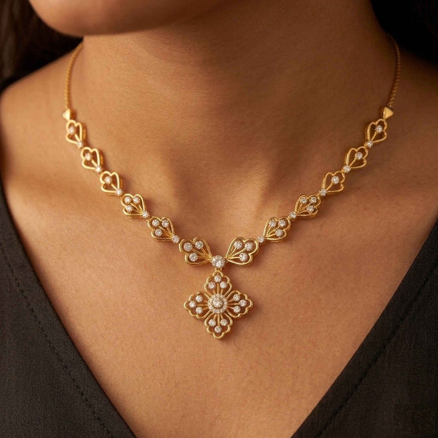 Gold and diamond necklace with floral pendant on a person wearing.