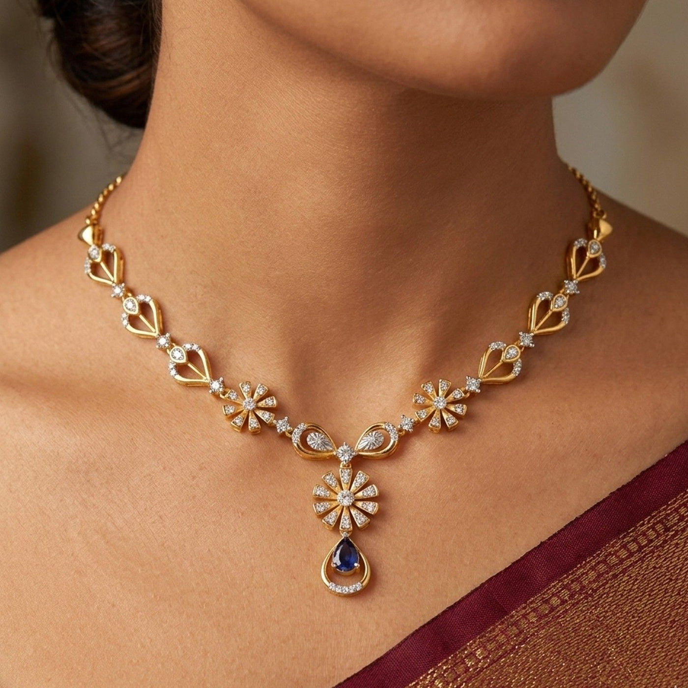 Gold and diamond necklace with a blue gemstone pendant on a person wearing a saree.