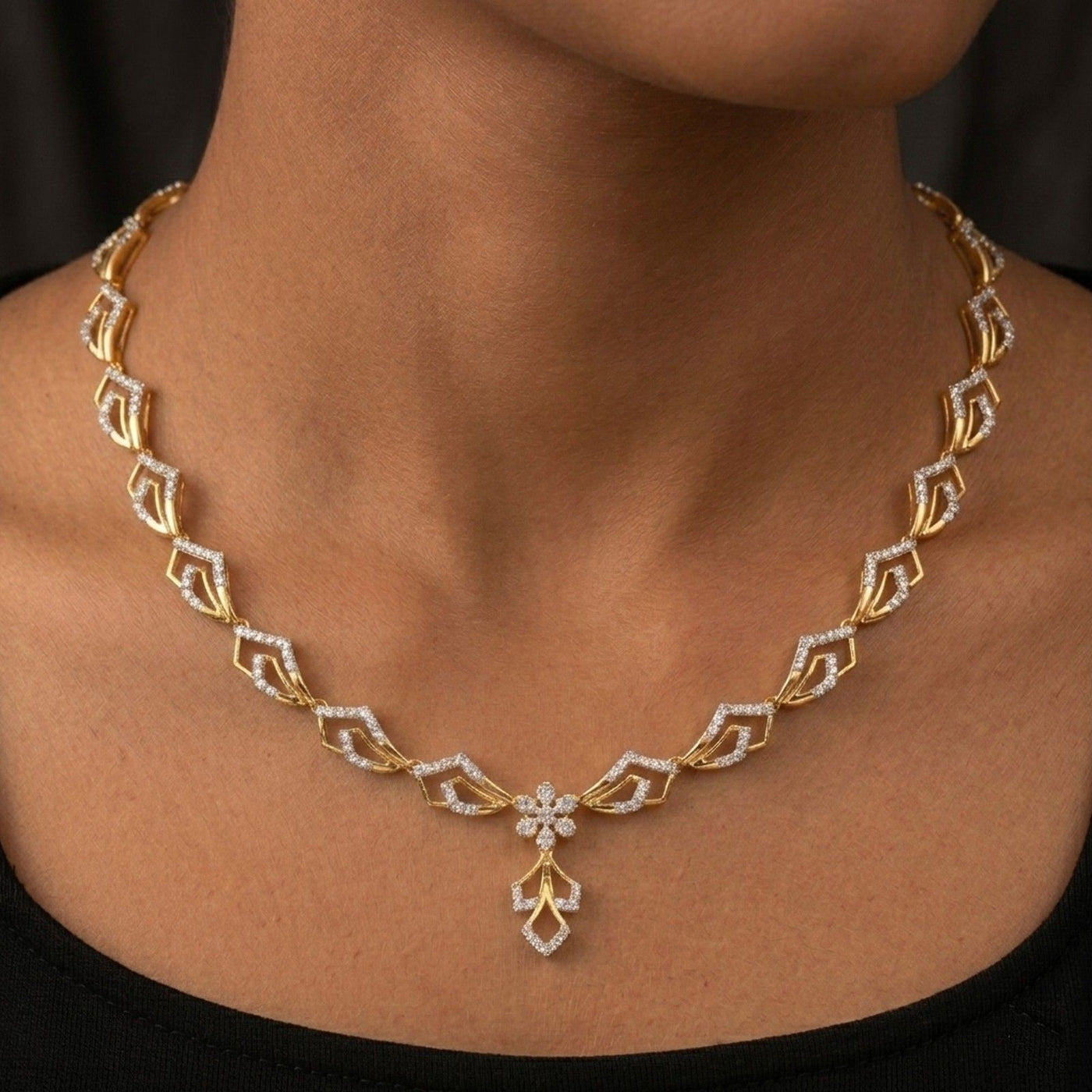 Gold necklace with diamond accents on a person's neck against a dark background