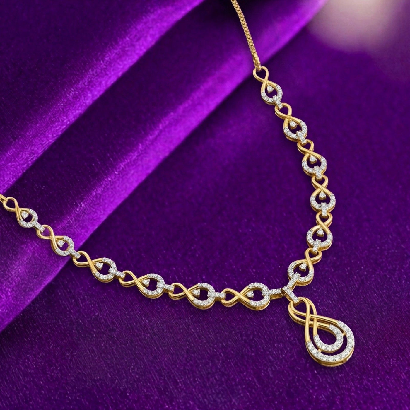 Gold necklace with diamond accents on a purple fabric background.