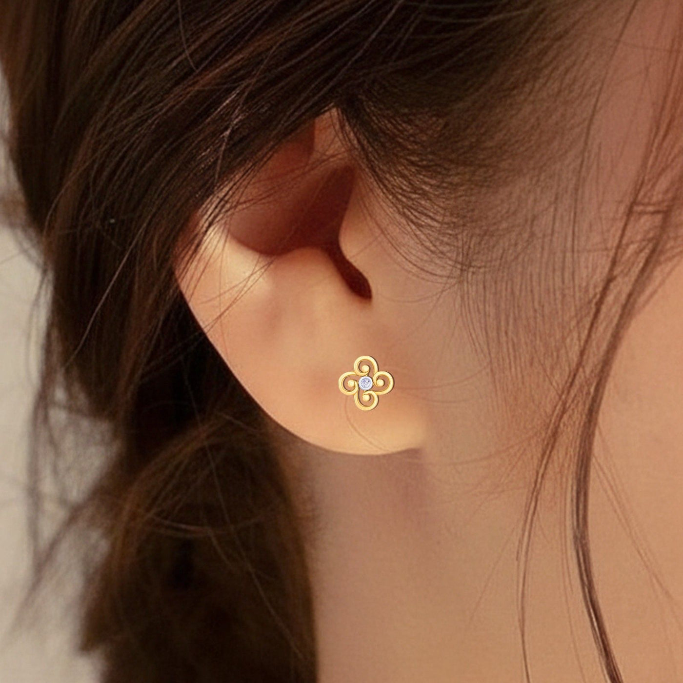 Close-up of a gold and diamond floral stud earring 