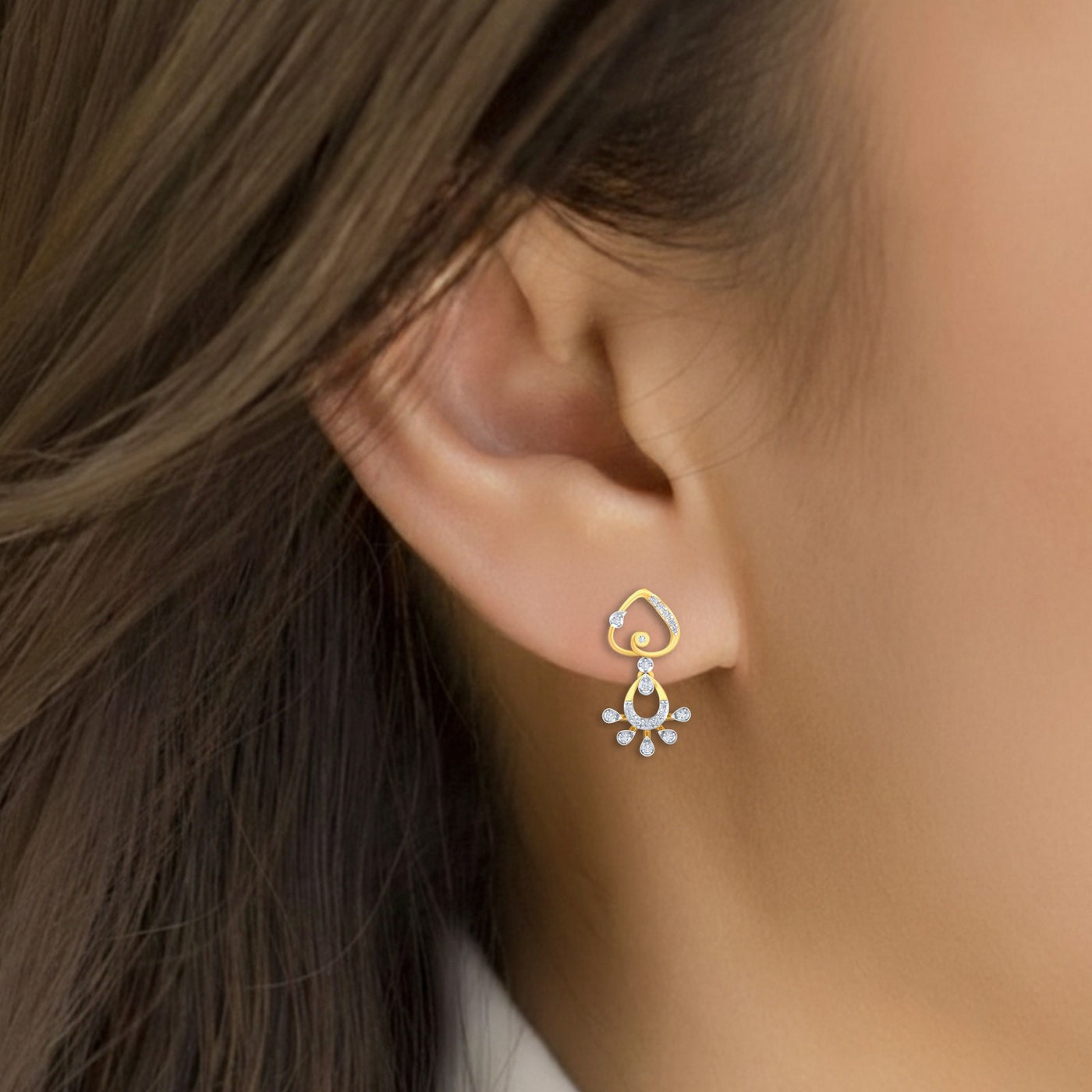 Close-up of an ear wearing a gold and diamond drop earring.
