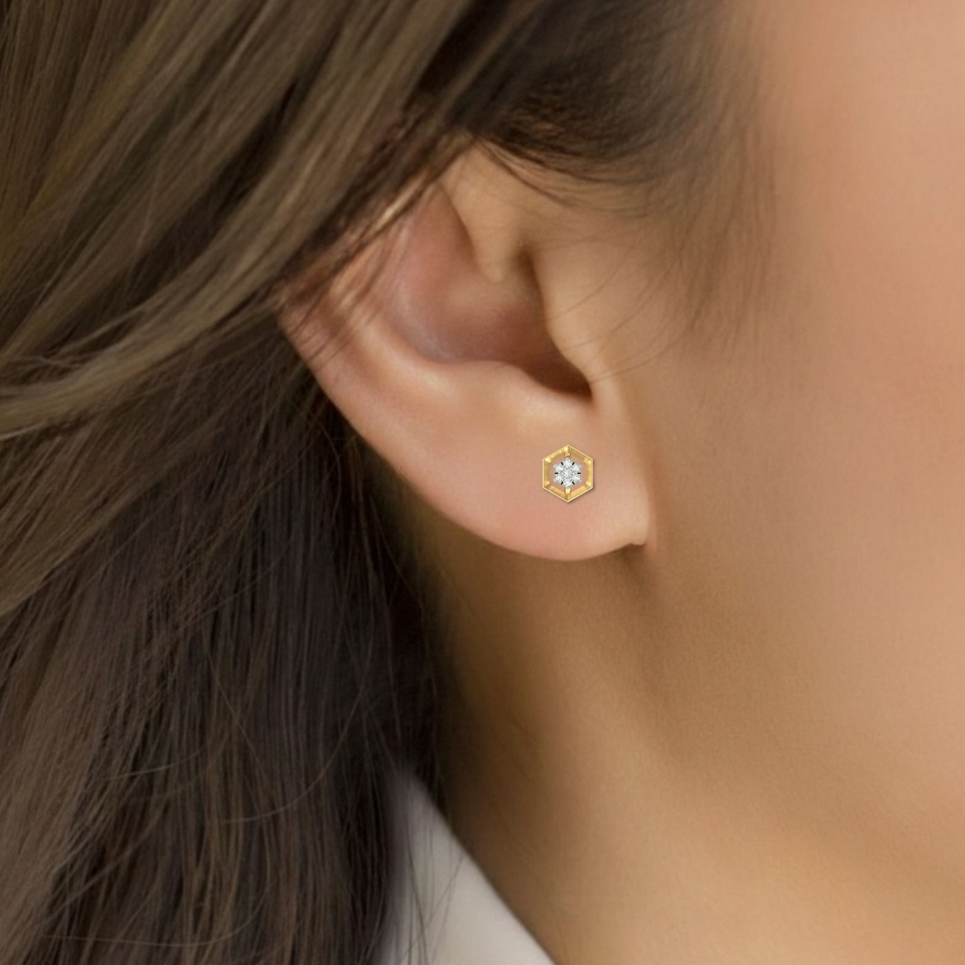 Close-up of an ear wearing a gold stud earring 
