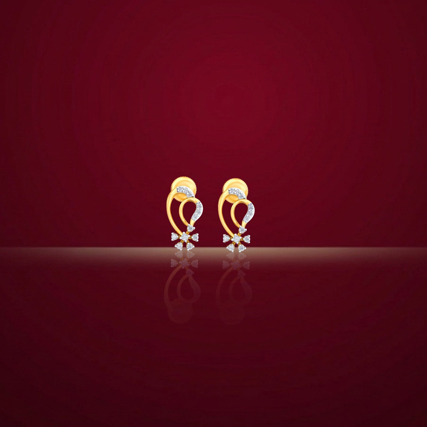 Gold and diamond stud earrings on a red background