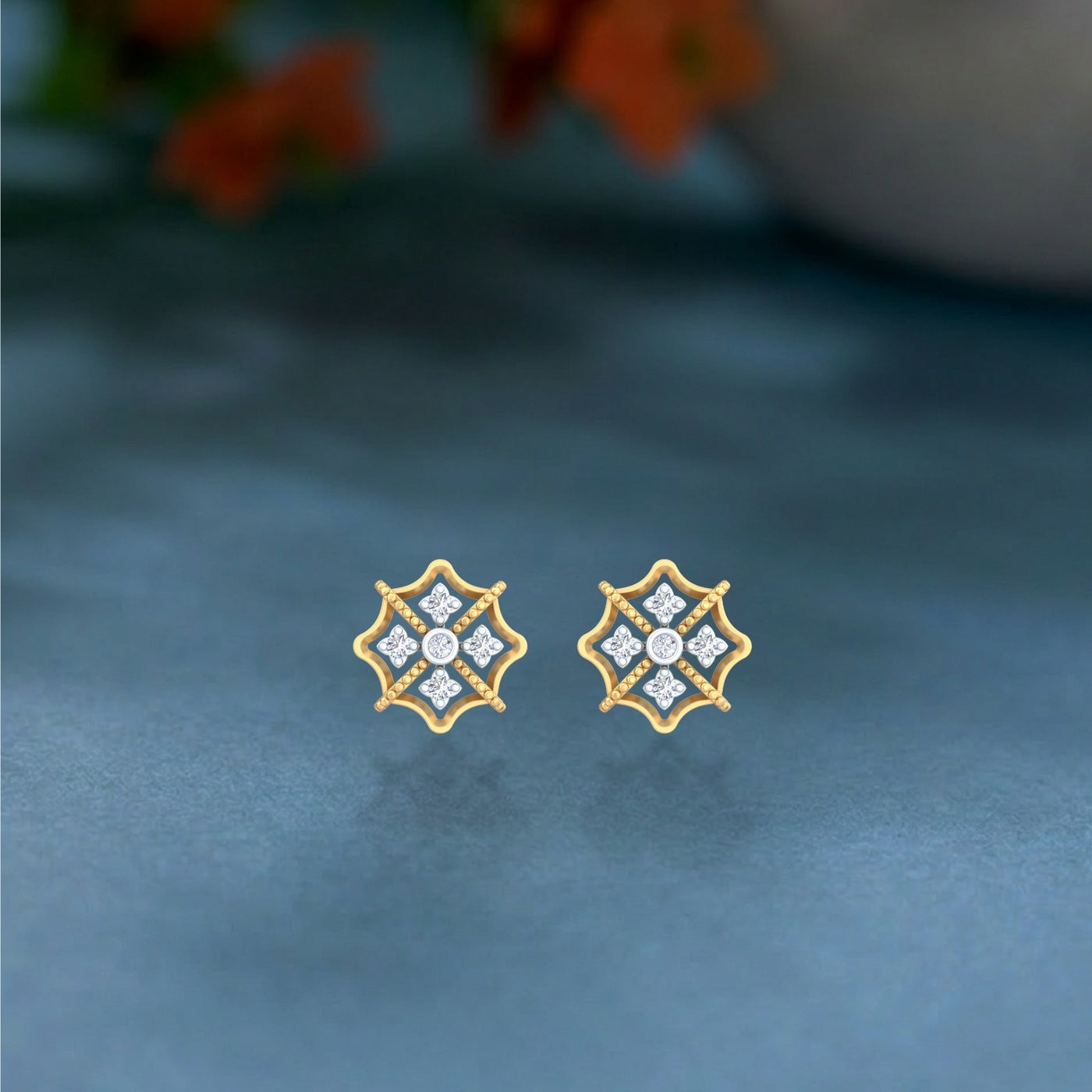 Gold and diamond stud earring with floral-design on a  blue background.