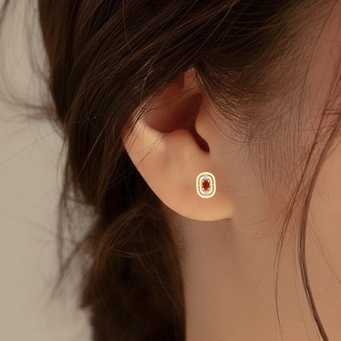 Close-up of an ear wearing a gold and diamond earring with gemstone.
