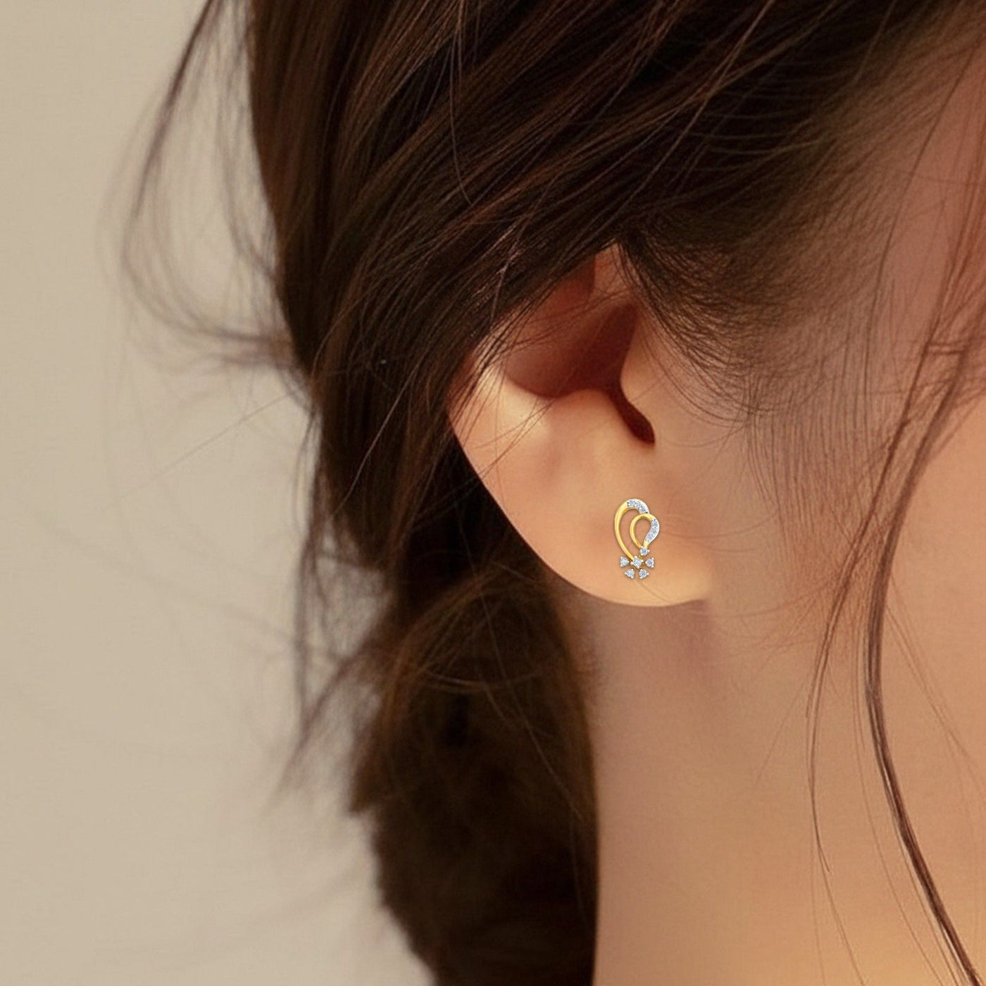 Close-up of an ear wearing a gold and diamond earring.