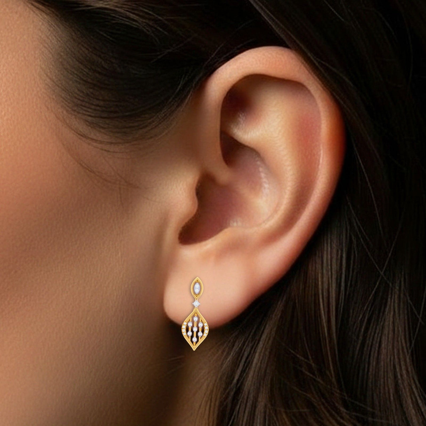 Close-up of an ear wearing a gold and diamond drop earring.
