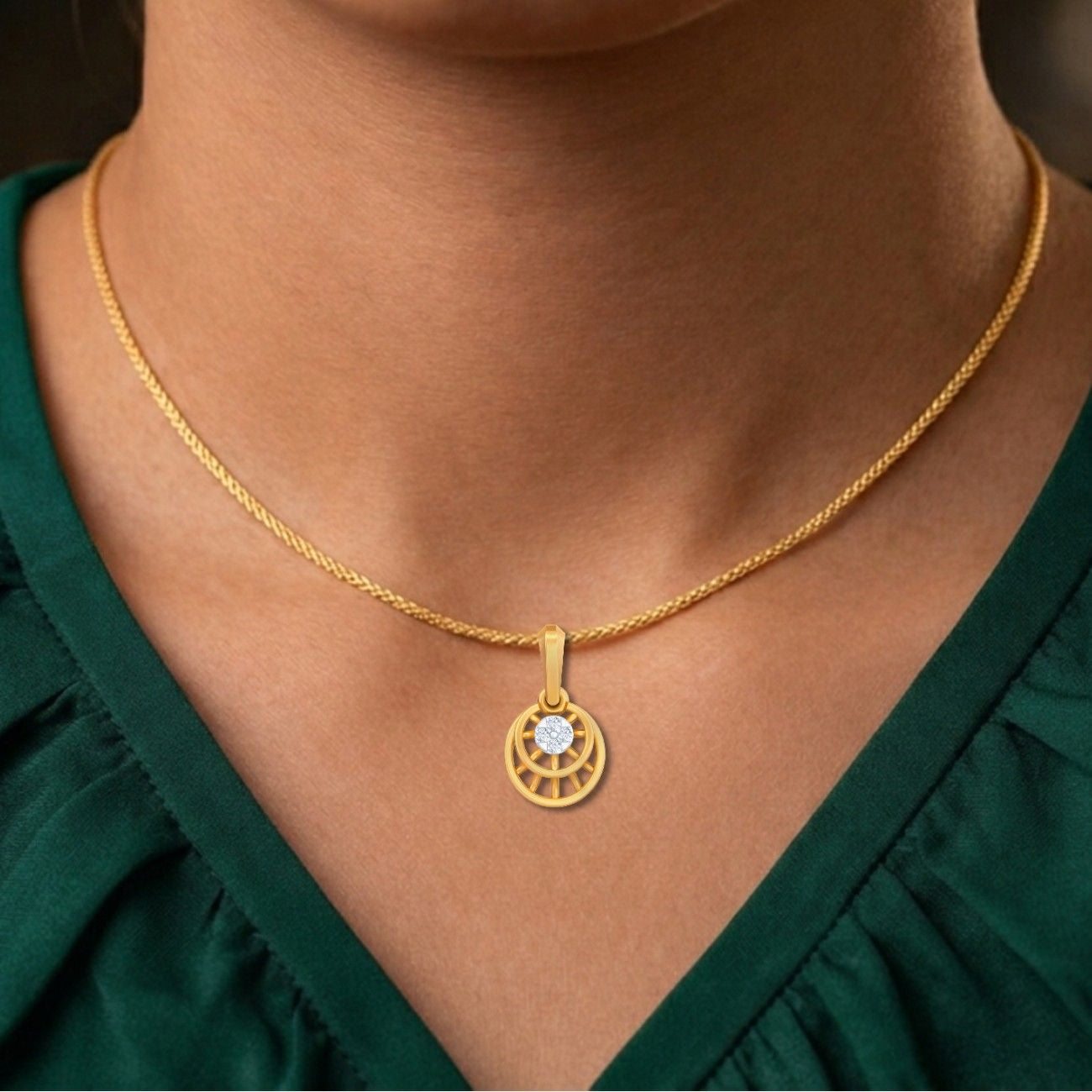 Gold necklace with a circular pendant worn by a person in a green top.
