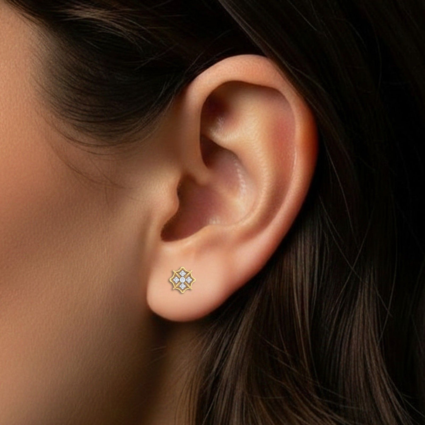 Close-up shot of a gold and diamond stud earring with floral-design.