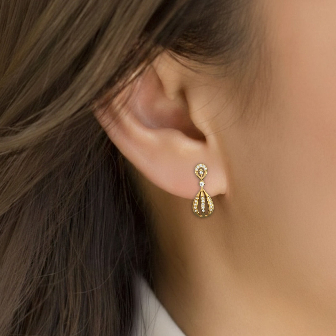 Close-up of an ear wearring a gold and diamond drop earring.