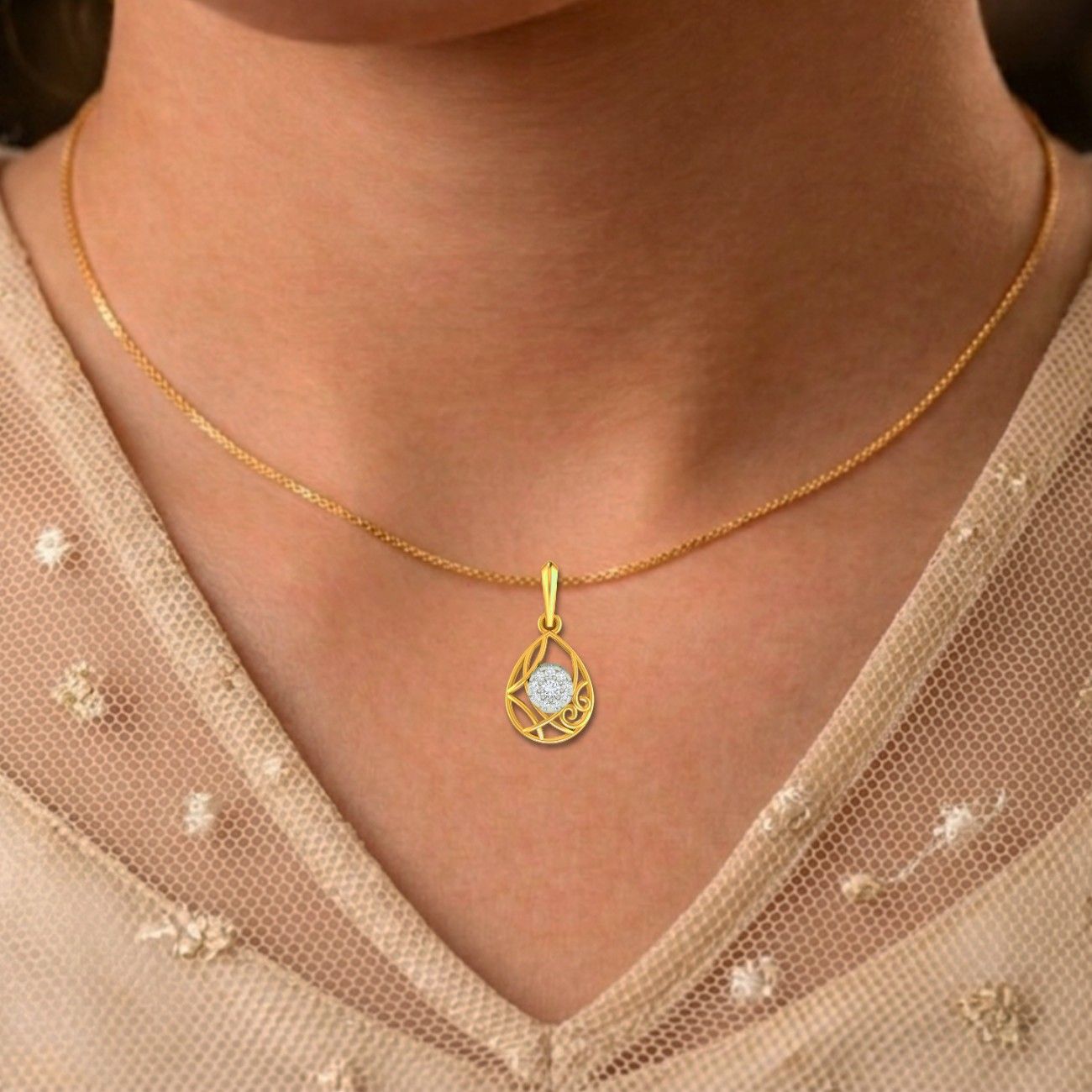 Gold necklace with a teardrop-shaped pendant worn by a person in a beige outfit.