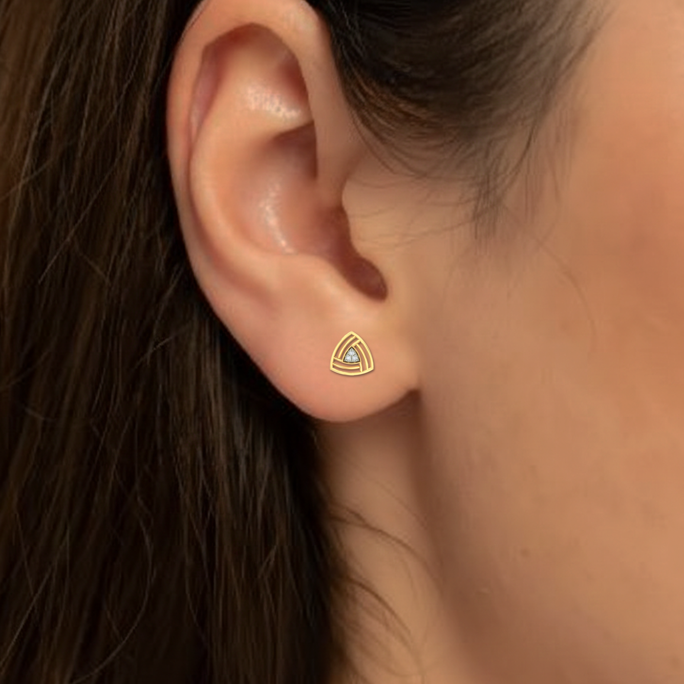 Close-up of an ear wearing a gold and diamond earring.