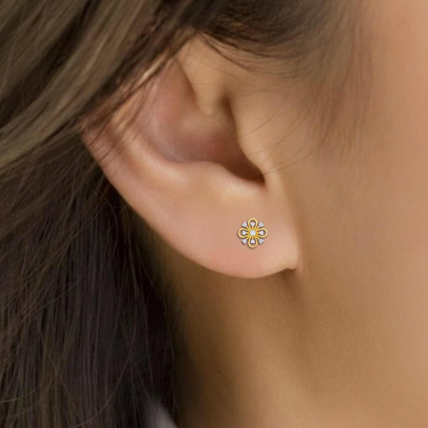 Close-up shot of a gold and diamond stud earring with floral-design.
