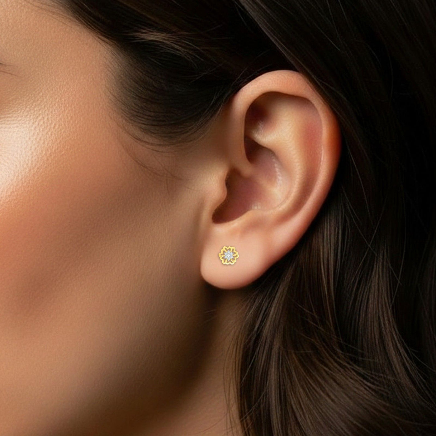 Close-up of an ear wearing a gold and diamond stud earring.