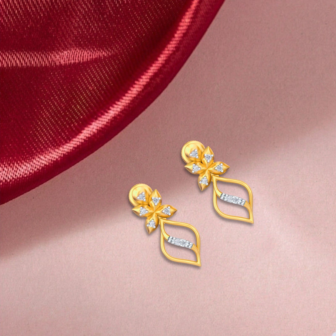 Gold and diamond drop earrings with floral design on a pink fabric background