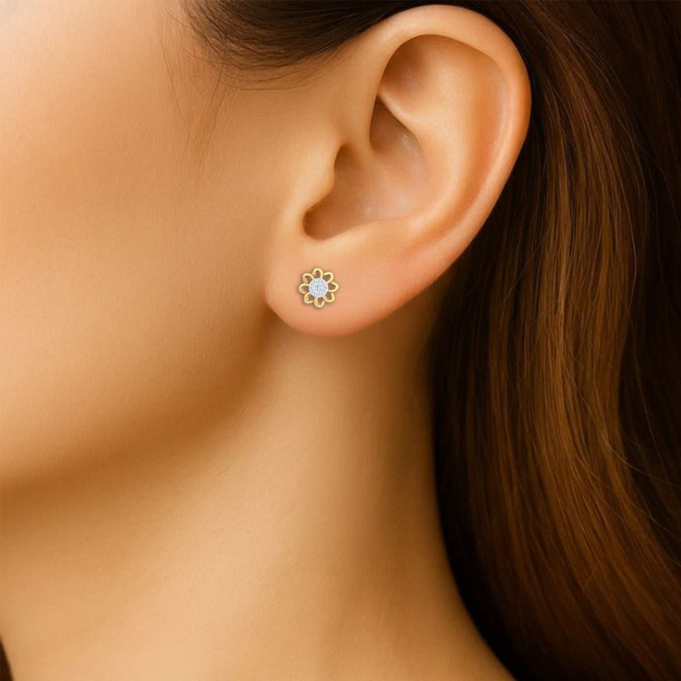 Close-up shot of a gold and diamond stud earring with floral-design.