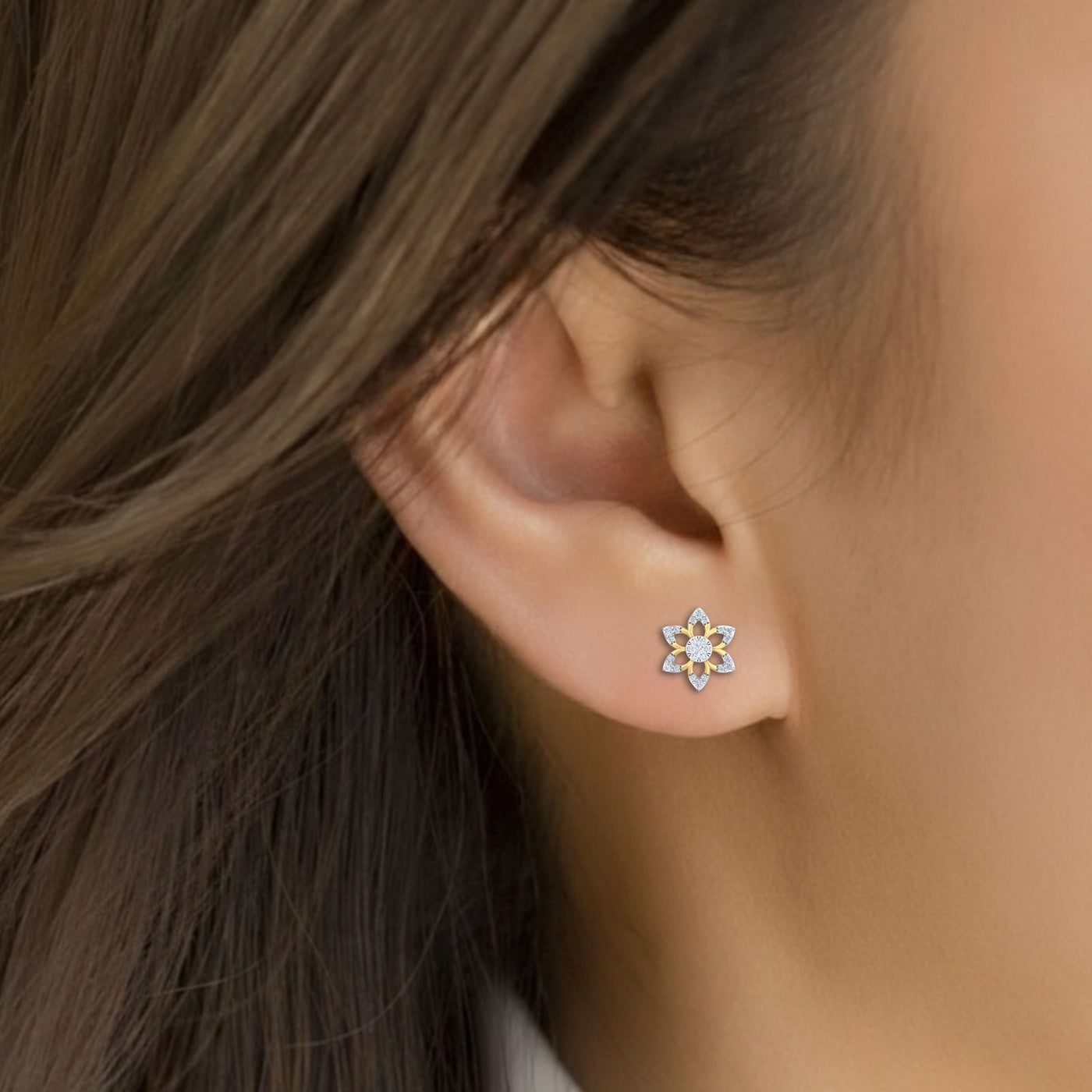 Close-up shot of a gold and diamond stud earring with floral-shaped.