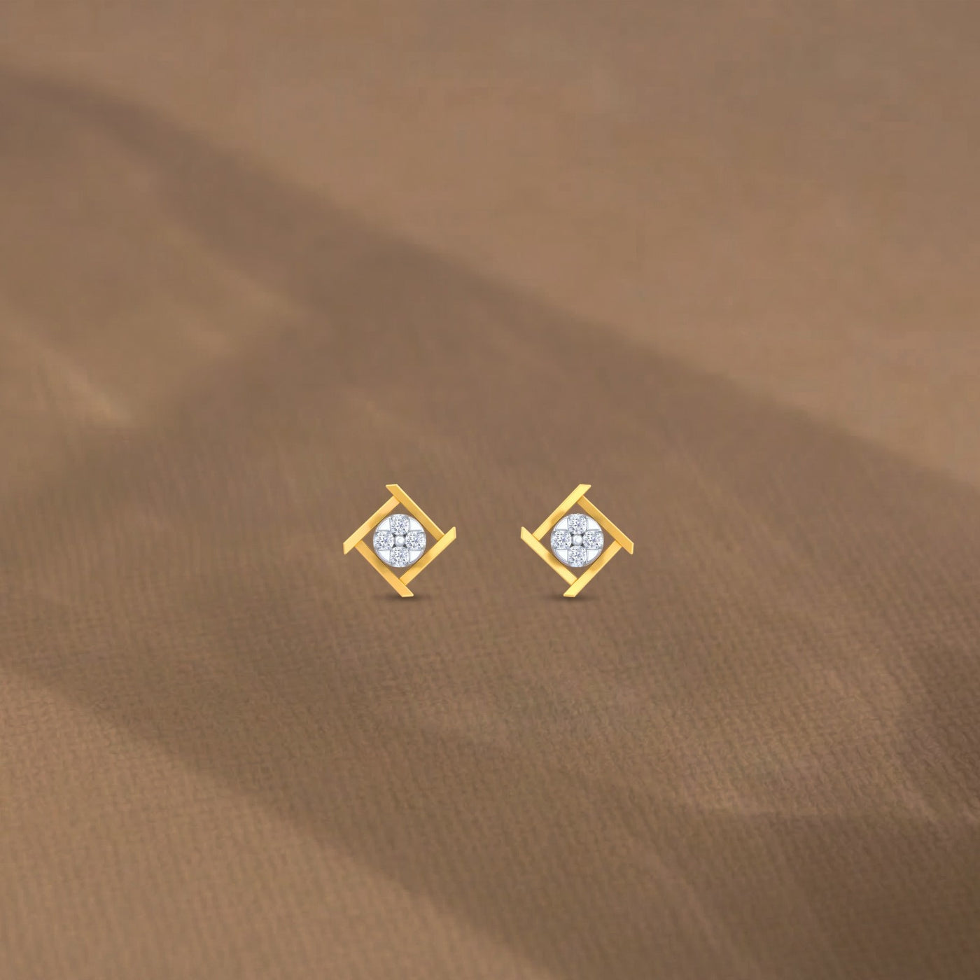 Gold and diamond earrings on a brown fabric background.