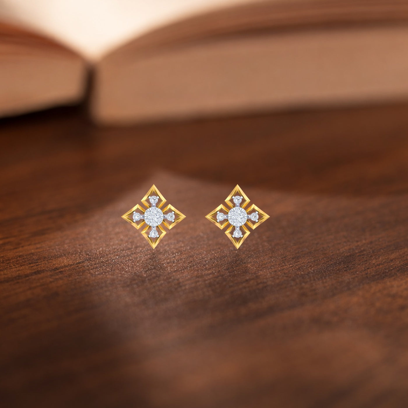 Gold and diamond stud earrings on a wooden surface.