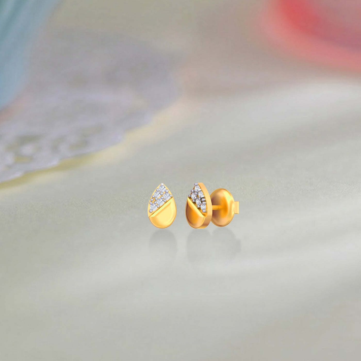 Gold and diamond stud earring with teardrop-shaped on a beige surface.