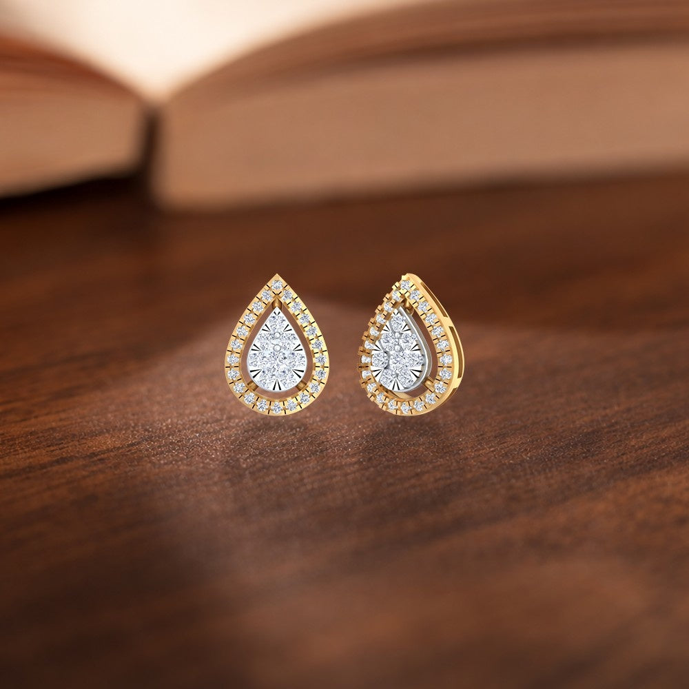 Gold and diamond teardrop-shaped earrings with diamond accents on a wooden surface.
