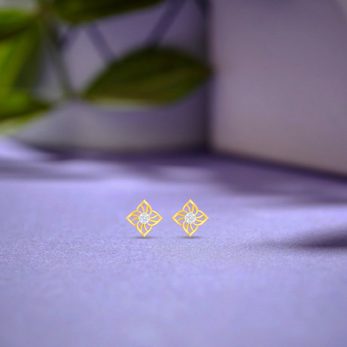 Gold and diamond floral stud earrings   on a textured surface.