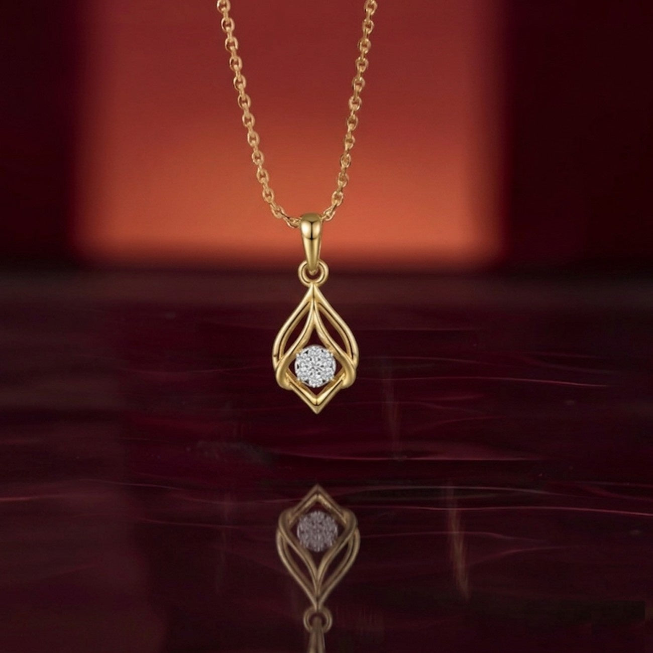Gold necklace with a diamond pendant on a reflective surface with a red background