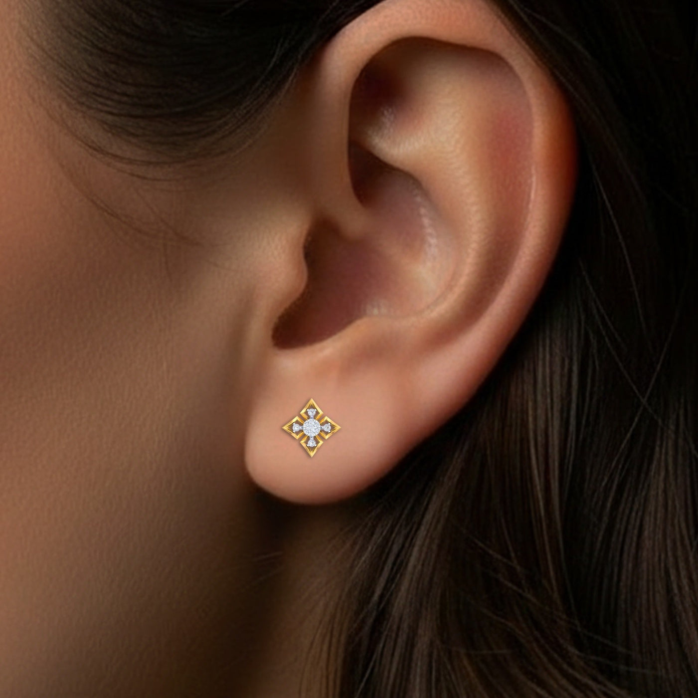 Close-up of an ear wearing a gold and diamond stud earring.