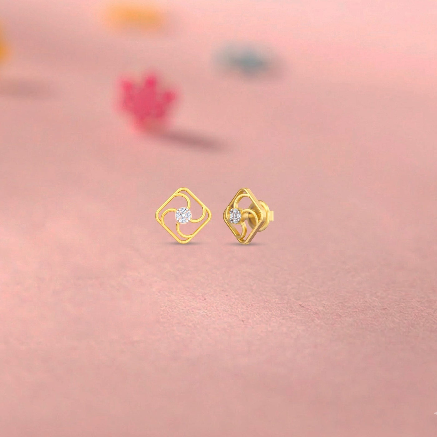 Gold and diamond stud earring on a pink background