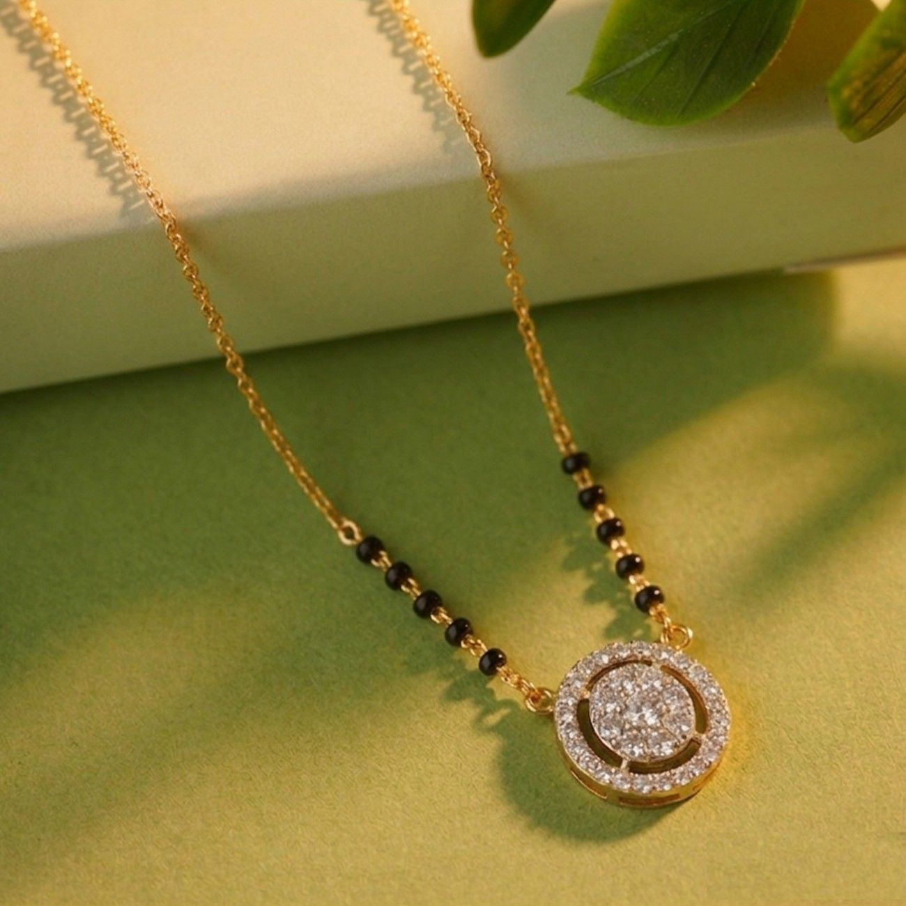 gold and diamond mangalsutra
with black beads on a green background