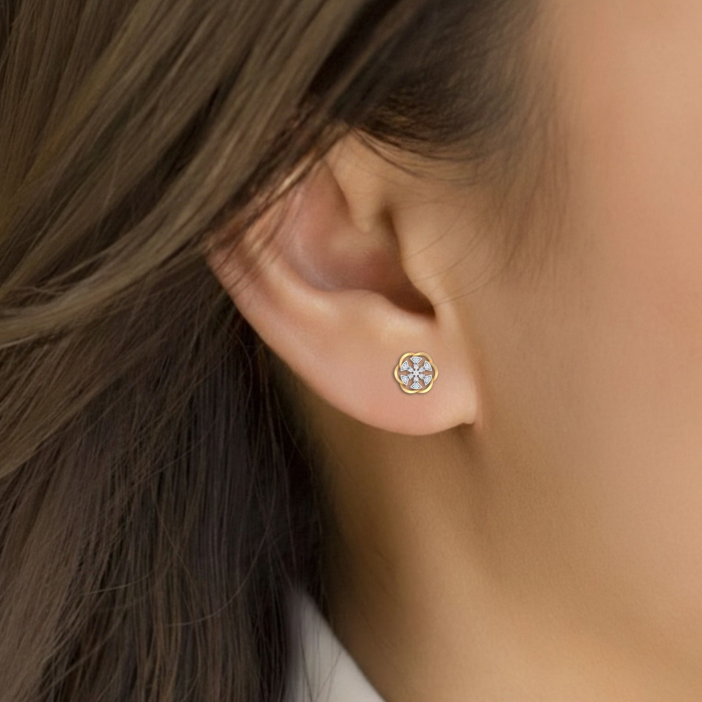 Close-up shot of a gold and diamond stud earring with floral-design.