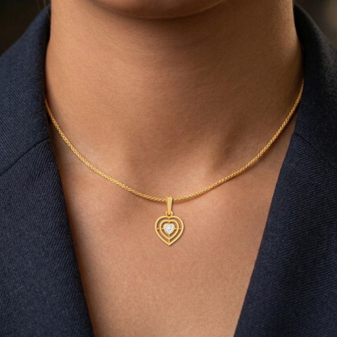 Gold necklace with a heart-shaped pendant worn by a person against a dark background