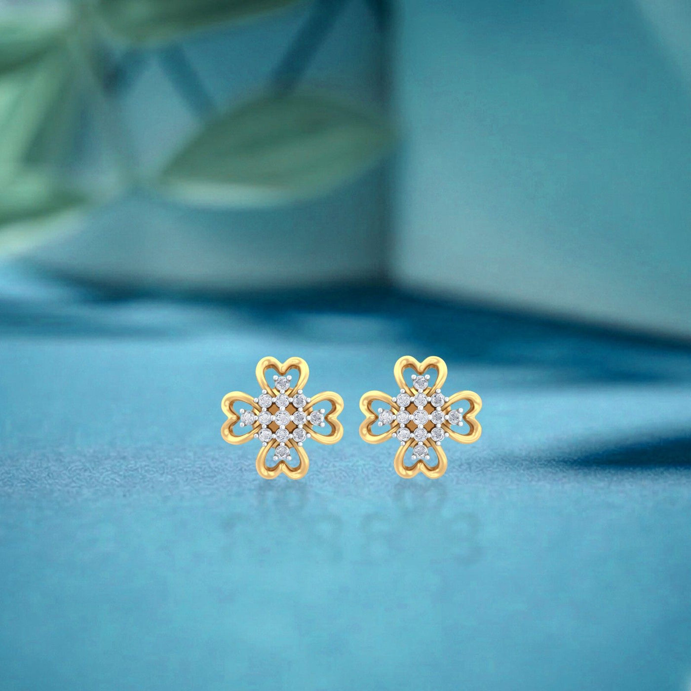 Gold and diamond stud earring with floral-design on a blue background.
