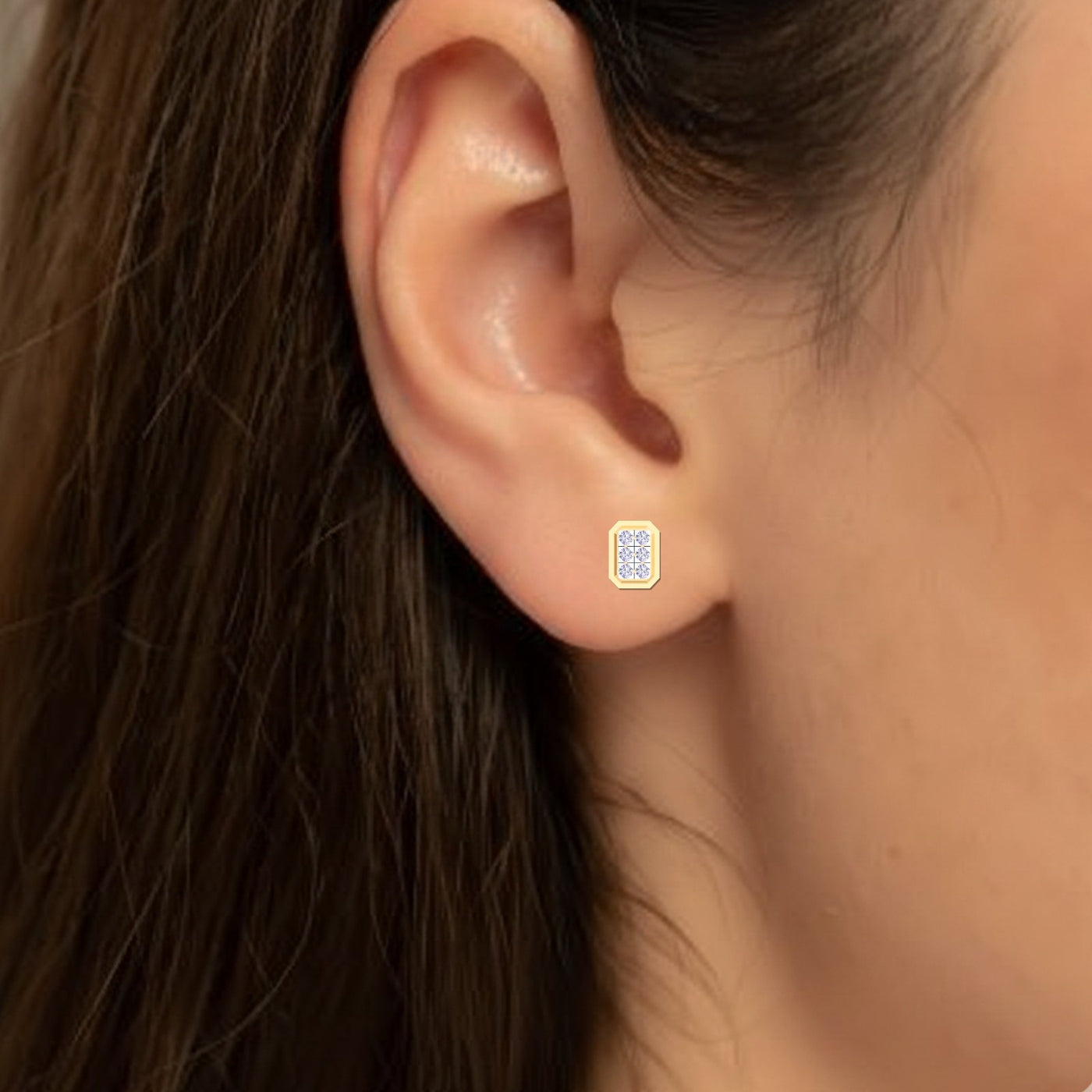 Close-up of an ear wearing a gold and diamond stud earring.