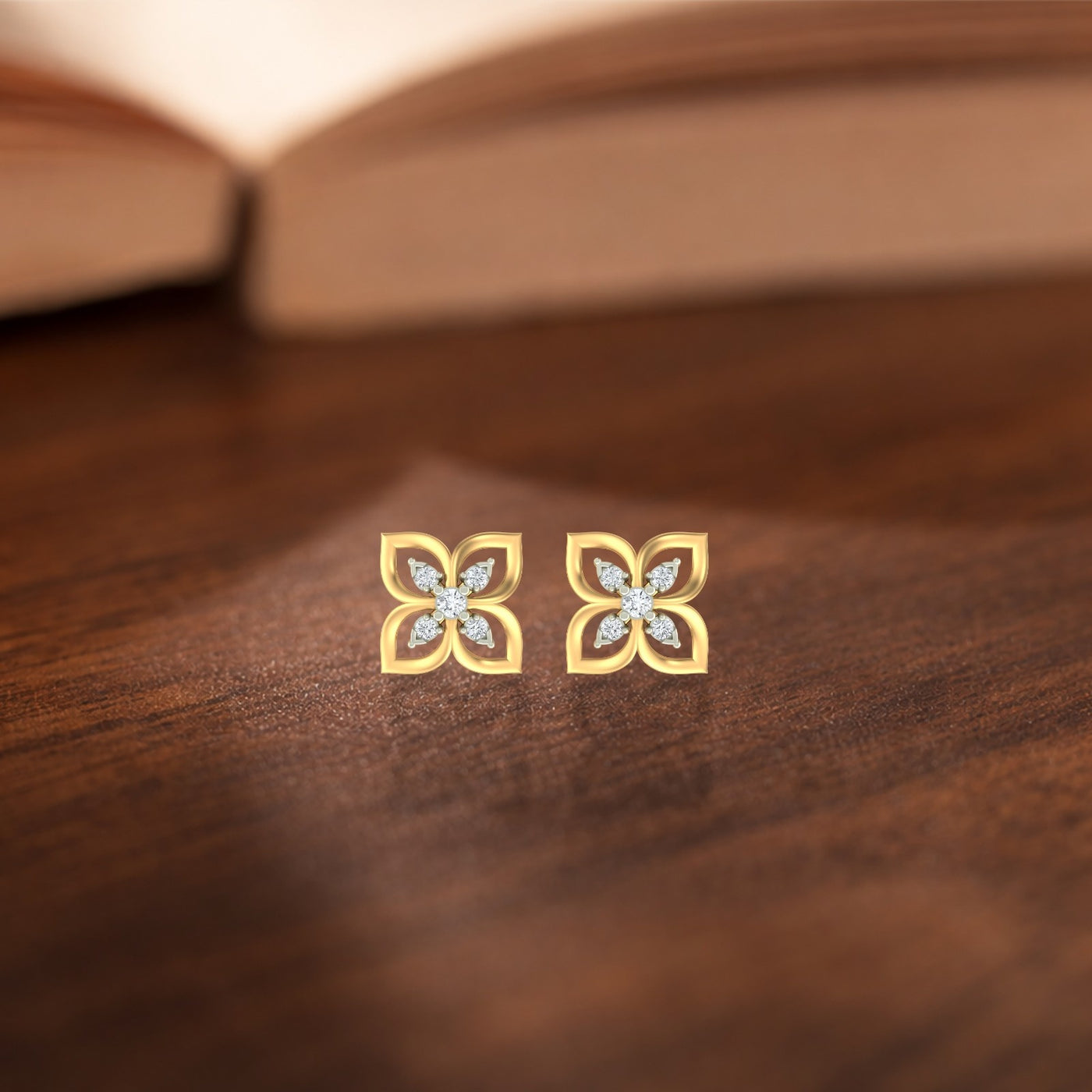 Gold and diamond floral stud earrings on a wooden surface