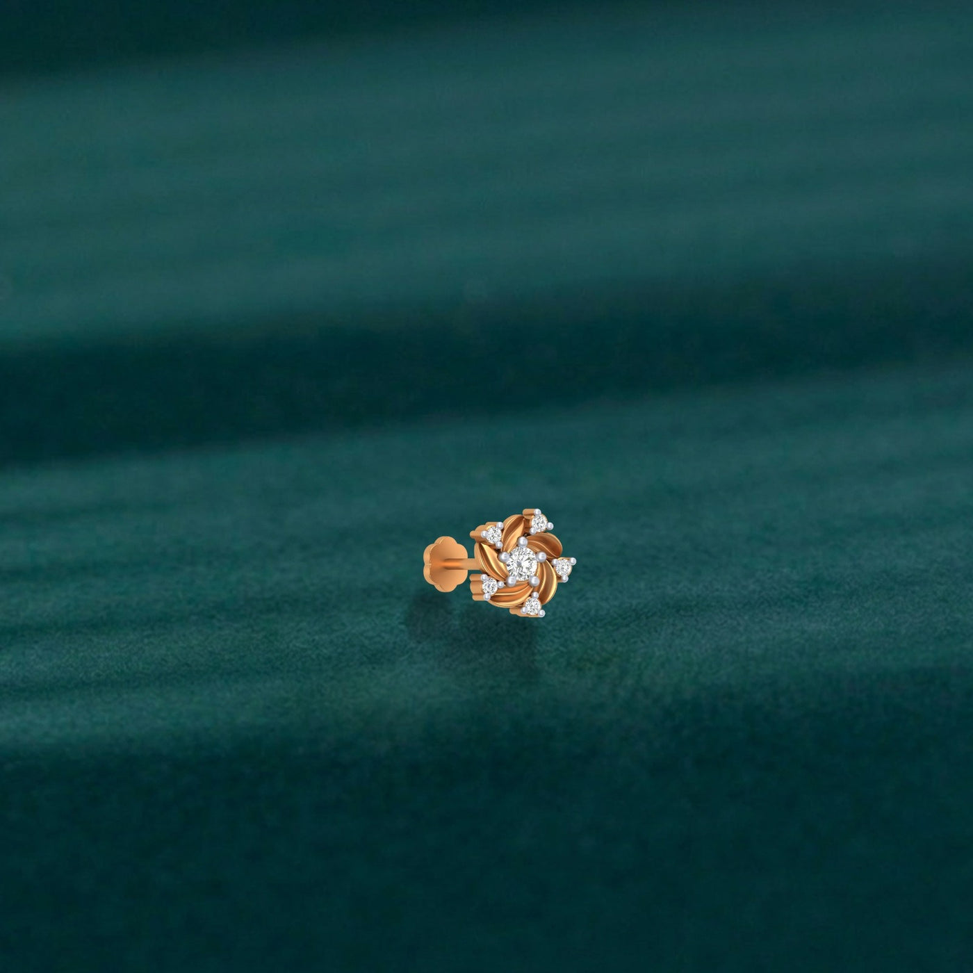 Yellow Gold and diamond stud nose pin on a teal fabric background