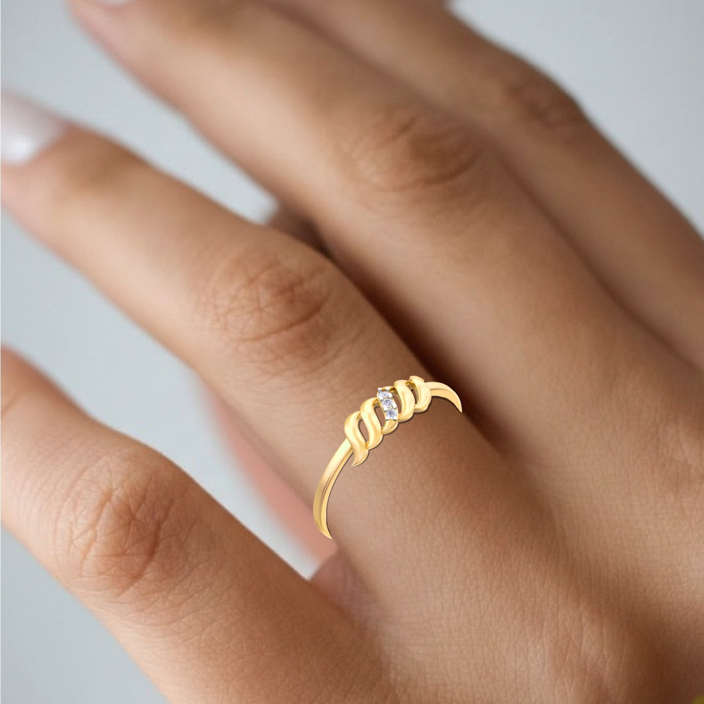 Gold ring with a small diamond on a person's finger against a neutral background