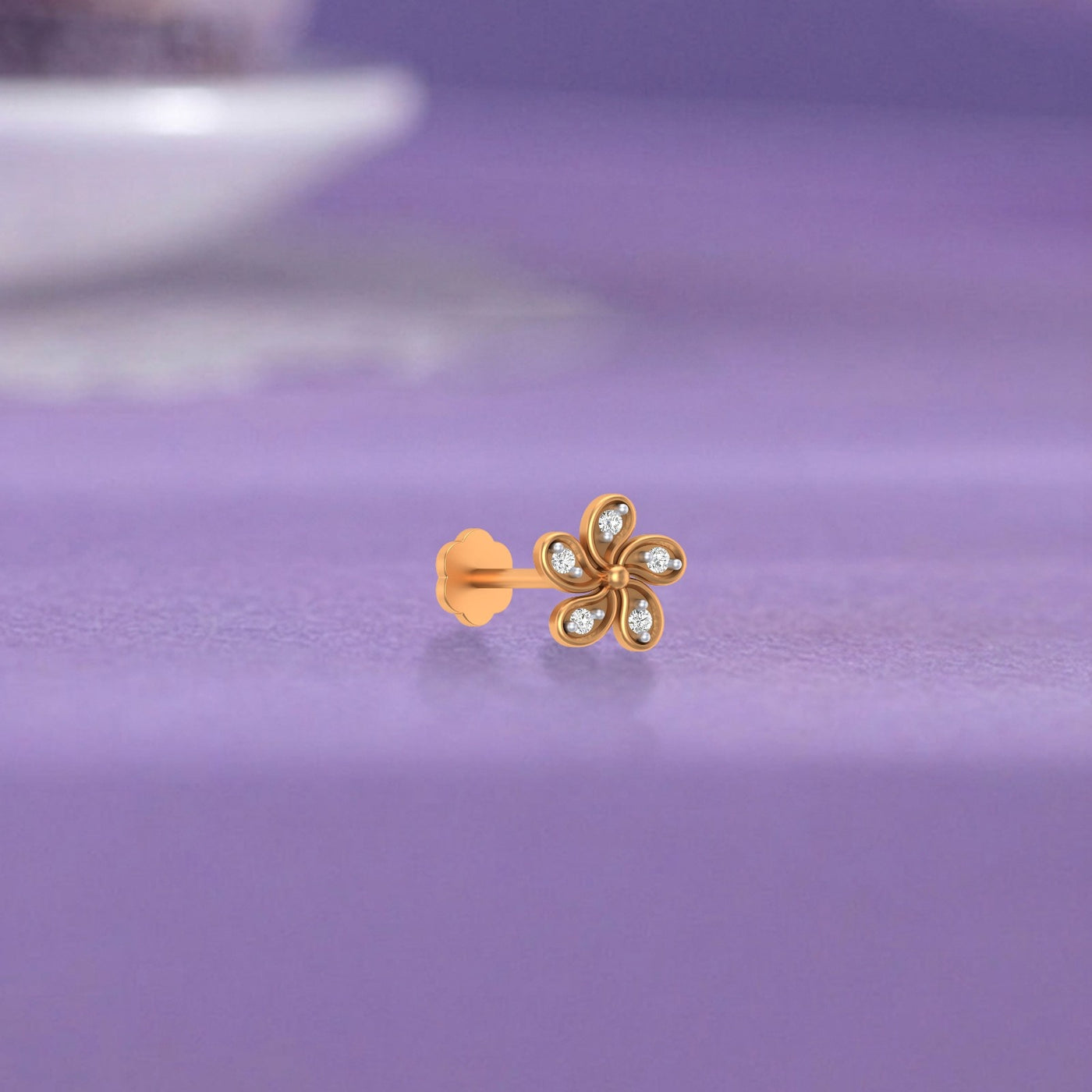 Yellow Gold and diamond stud nose pin flower-shaped  on a purple surface