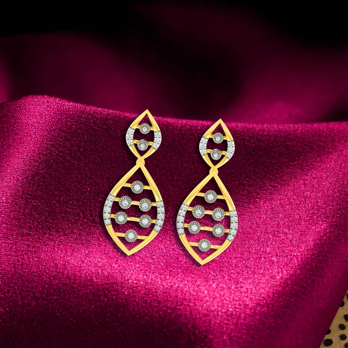 A pair of gold teardrop-shaped dangler earrings, displayed on a rich red satin fabric background.