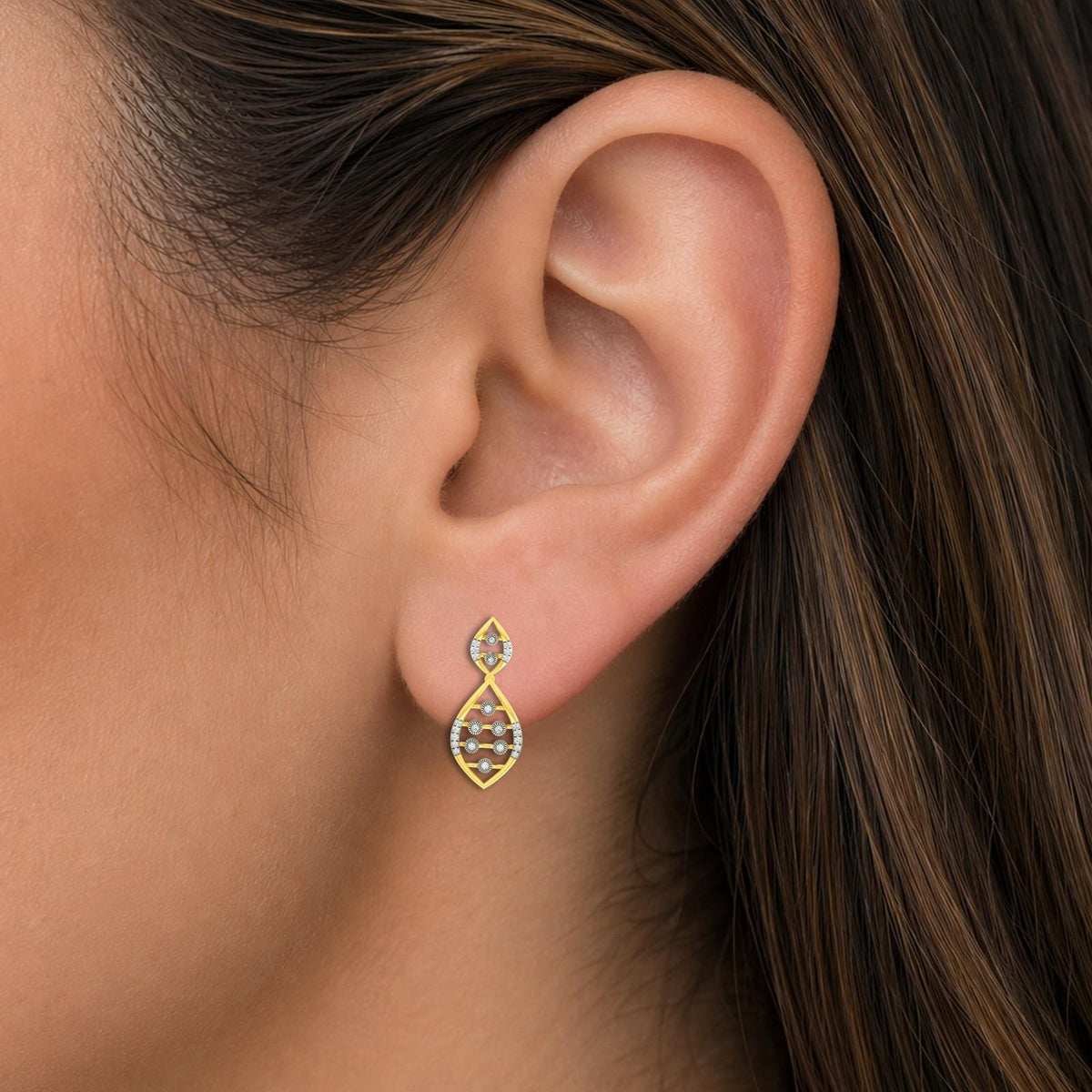 A close-up of a model's ear wearing a gold teardrop-shaped stud earring.